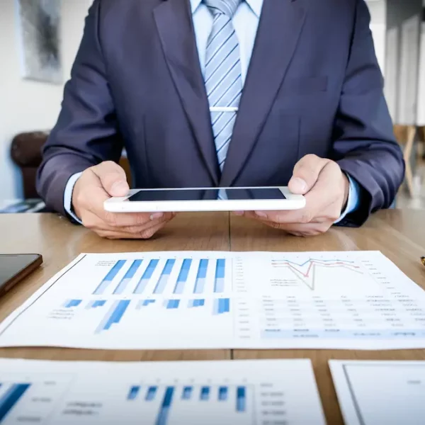 multitasking-handsome-young-man-working-with-touchpad-while-sitting-couch-office-financial-statistic-graph